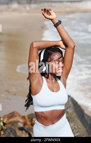 Bonne tenue excitée jeune sportswoman debout sur la plage et de profiter brise marine après l'entraînement Banque D'Images