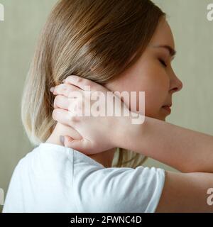 La femme tient le cou avec douleur spasme du muscle cervical à la main. Douleurs au cou, vertèbres cervicales, maladie du système musculo-squelettique chez la jeune femme. Carré Banque D'Images