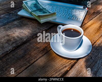 Une tasse de café et d'argent avec un ordinateur portable se trouve sur une table en bois. Banque D'Images