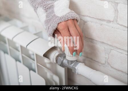 La femme ouvre la vanne du chauffage du radiateur. Banque D'Images