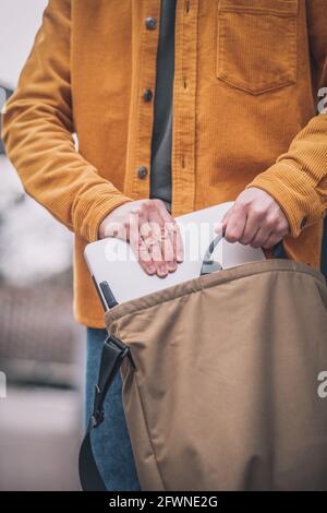 Gros plan de la main de homme mettant l'ordinateur portable dans un sac Banque D'Images