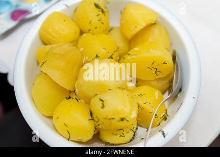 Jeunes pommes de terre bouillies avec beurre et aneth dans un bol en argile sur fond de bois. Fermez de délicieuses pommes de terre neuves arrosées d'aneth finement hachées Banque D'Images