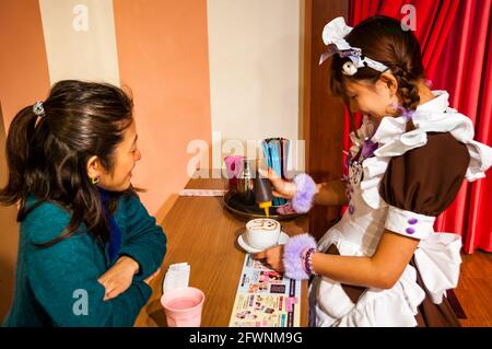 Notre femme Chimu dessine un lapin au caramel sur le dessus d'un café @Home un maid café d'Akihabara à Tokyo district Banque D'Images