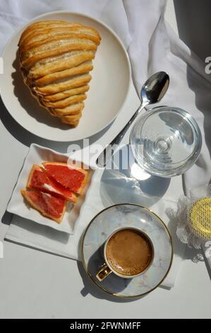 Plat de petit déjeuner avec café, pâtisserie, verre d'eau, pot de miel et pamplemousse Banque D'Images