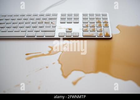 Projections de café noir sur un clavier d'ordinateur blanc Banque D'Images