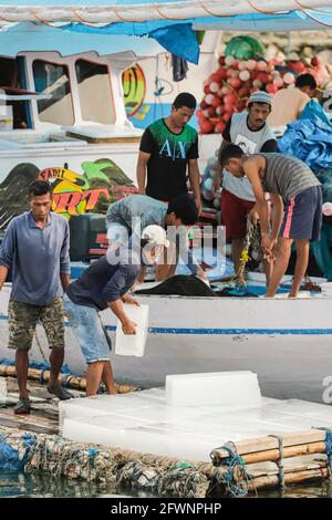Les pêcheurs chargent des blocs de glace pour les emballer sur un bateau de pêche dans le port très animé de cette ville balnéaire à l'extrême sud ; Tanjung Bira, Sulawesi du Sud, Indonésie Banque D'Images