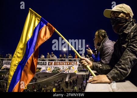 Un manifestant détient un drapeau colombien pendant la manifestation.le 21 mai, après 24 jours de grève, les manifestants continuent de manifester dans les rues de Bogotá et s'opposent à la nouvelle réforme fiscale. Au cours de la journée, à la « porte des Amériques » rebaptisée « porte de la résistance », l'un des nombreux points de démonstration, des milliers de personnes ont participé à une grève pacifique. Différents événements tels que concerts, spectacles et discours ont fait de cet endroit une place joyeuse. À 10 h, la police nationale et l'ESMAD (escadron anti-émeute) sont arrivés à la manifestation avec quatre véhicules armés qui attaquent des manifestants avec du canon à eau Banque D'Images