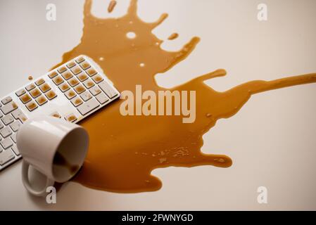 Café noir renversé sur un clavier d'ordinateur à un blanc tableau Banque D'Images