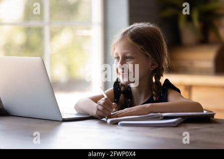 Joyeux enfant sucré qui étudie à la maison, fait ses devoirs à l'école Banque D'Images