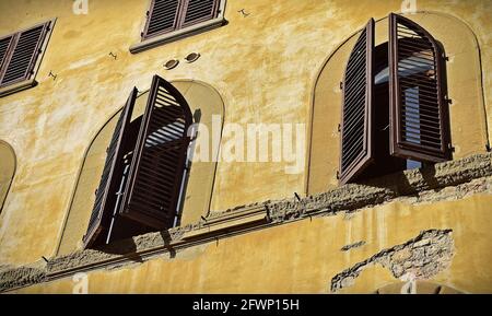 FLORENCE, ITALIE - 06 février 2016 : les stores de fenêtre en bois s'ouvrent légèrement dans la façade d'un ancien bâtiment à Florence, Italie. Façade peinte en jaune avec arc Banque D'Images