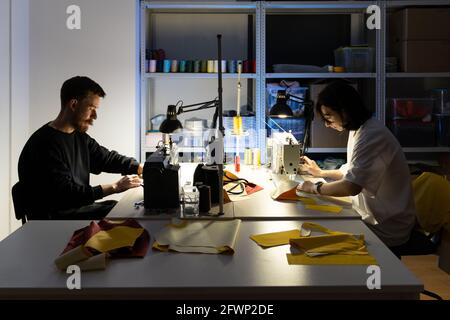 Jeunes créateurs de vêtements au travail. Les tailleurs professionnels homme et femme se sont cousus sur des machines à coudre Banque D'Images