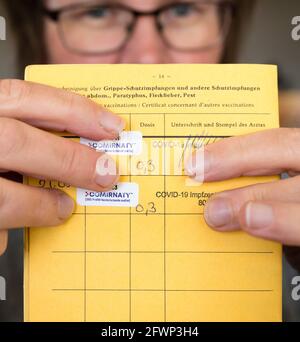Une femme caucasienne détient son certificat international de vaccination avec deux confirmations de vaccination Covid-19 (Pfizer, numéros de série retirés) Banque D'Images