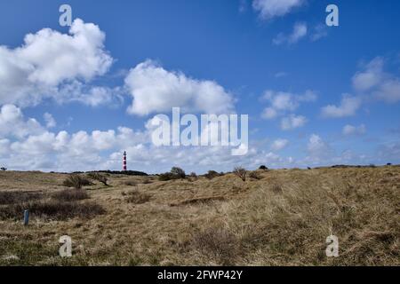 Vallée de la dune avec l'herbe de plage et un ciel bleu et en arrière-plan un classique, historique vieux phare rouge et blanc. Jour ensoleillé venteux, nuages turbulents Banque D'Images