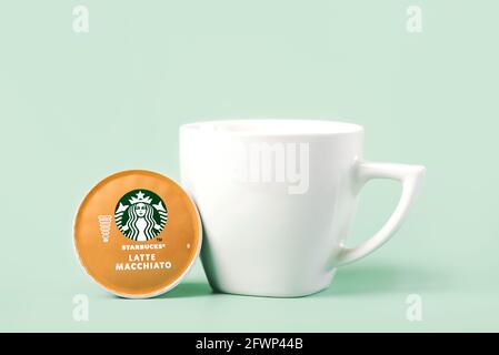 Capsule de café Starbucks Latte Macchiato à côté d'une tasse blanche de café sur fond vert Banque D'Images