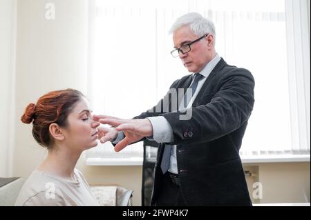 Homme mûr à cheveux gris hypnotises femme caucasienne pendant la séance d'hypnothérapie. Le psychologue utilise des traitements alternatifs pour l'esprit subconscient Banque D'Images