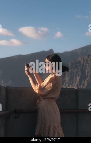 fille en robe jaune et lunettes de prise de photo avec mobile Banque D'Images