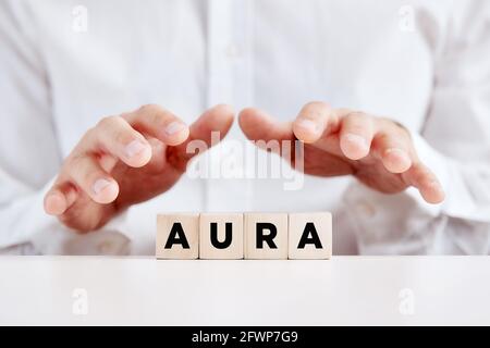 Homme tenant ses mains de manière protective sur les cubes de bois avec le mot aura. Concept de guérison spirituelle. Banque D'Images