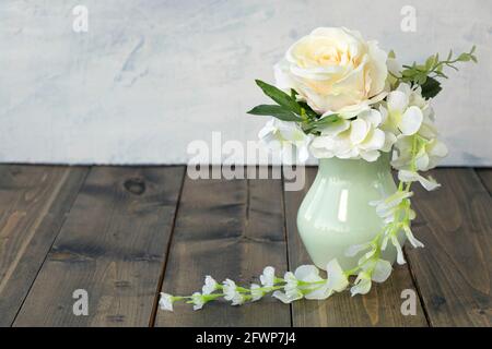 Bouquet de rose pêche et d'hortensia blanc dans un vase vert pastel sur fond de bois avec espace de copie. Concept joyeux anniversaire ou vacances. Mise au point douce Banque D'Images