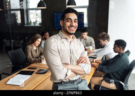 Jeune homme d'affaires barbu assis sur le bureau et posant Banque D'Images