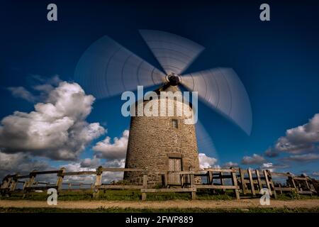 Moulin à vent idyllique dans la région normande de france avec déménagement lames et nuages en arrière-plan Banque D'Images