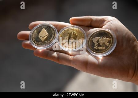 Jeune homme tenant des jetons Crypto Bitcoin, Ethereum, Ripple au creux de la main - crypto-monnaie et concept d'actif numérique Banque D'Images