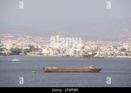 vieux navire rouillé couché pour l'ancre dans la baie avec la ville sur la pente de la montagne en arrière-plan Banque D'Images