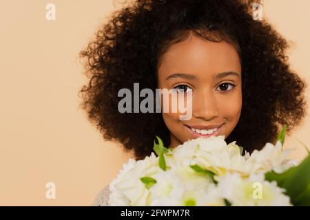 jolie jeune fille afro-américaine avec bouquet de pâquerettes isolées sur beige Banque D'Images