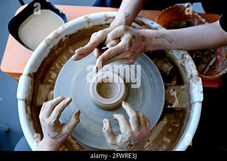 De belles mains de femmes et d'adolescents au-dessus de la roue de potier. Sculptez de l'argile dans un atelier de poterie. Poterie traditionnelle. Atelier de céramique conce Banque D'Images