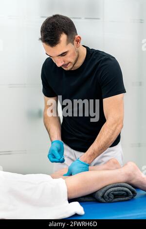 Jeune travailleur de médecine faisant l'acupuncture procédure à la cliente de la clinique de physiothérapie. Banque D'Images