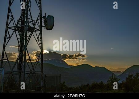 Silhouette des antennes et des répéteurs de signaux de téléphone et de télévision au coucher du soleil. Abruzzes, Italie, Europe Banque D'Images