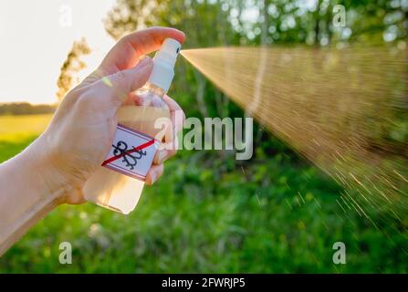 Vue rapprochée de la femme tenant la main et utilisant un produit anti-moustiques à base d'huile maison en plein air dans la forêt. Banque D'Images