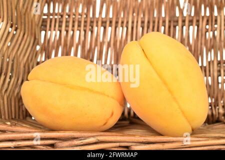 Deux abricots d'ananas juteux dans un panier de brindilles, gros plan. Banque D'Images