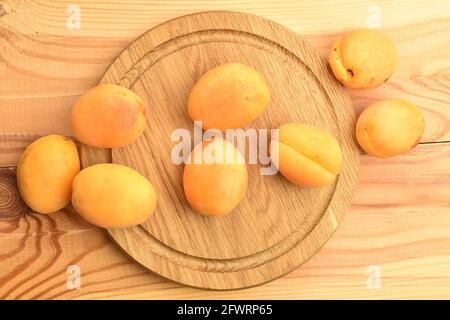 Plusieurs abricots d'ananas mûrs jaunes sur un plateau en bois, gros plan, sur une table en bois, vue de dessus. Banque D'Images