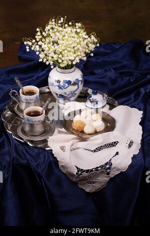 Encore la vie avec un bouquet de lys de la vallée et tasses de café sur soie bleue Banque D'Images