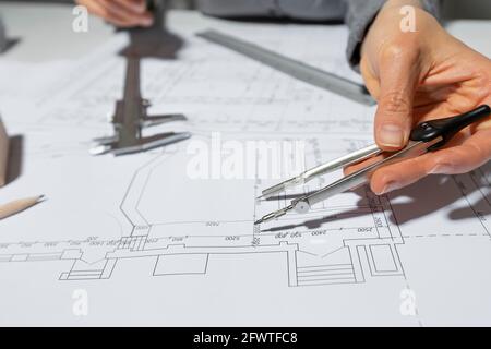 L'architecte mesure avec un séparateur pour dessiner sur du papier. Le concepteur dessine une esquisse du projet de la salle. Banque D'Images