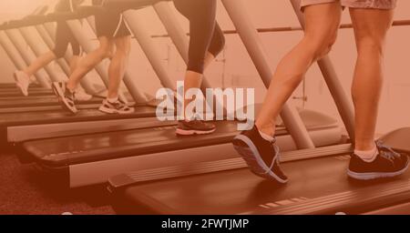 Composition de la partie basse des personnes en salle de gym tapis roulant avec fond de couleur orange Banque D'Images