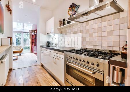 Cuisine avec armoires blanches et comptoir noir avec grand cuisinière à gaz dans un appartement moderne Banque D'Images