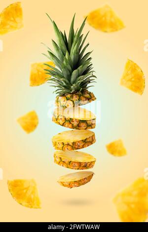 Tranches d'ananas frais volantes avec des morceaux sur fond jaune. Concept alimentaire créatif. Banque D'Images