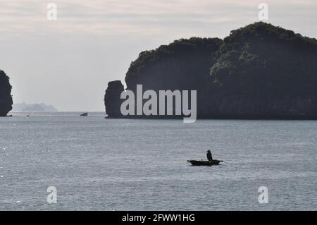 Un pêcheur dans un petit bateau à Ha long Bay, Vietnam. Banque D'Images