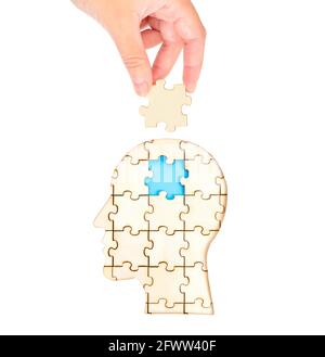 Main femelle plaçant la pièce manquante du cerveau du puzzle formant une tête humaine isolée sur blanc. Concept de traitement mental et de thérapie. Banque D'Images