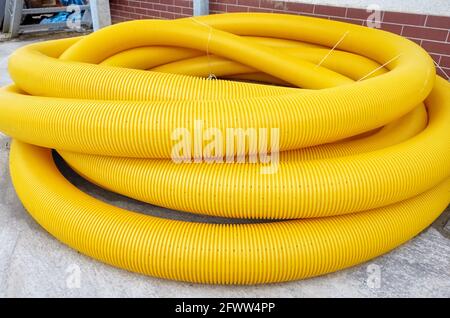 Tuyau de drainage de terre de bobine jaune sur le sol, il est utilisé pour enlever l'eau excessive des champs et des jardins. Banque D'Images