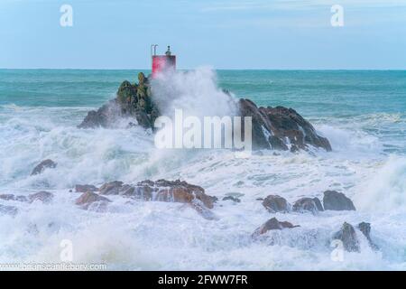 Structure rouge de balise sur North Rock enveloppée dans la mer Et vaporisez la base du mont Maunganui avec sauvage spectaculaire la mer de tempête s'est écrasant autour et au-dessus Banque D'Images