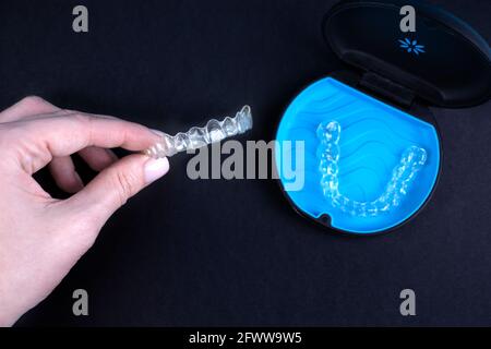 Femme tenant des aligneurs transparents invisibles invisalign ou des appareils orthodontiques en plastique. Boîtier noir avec boîtier, fixations en plastique transparent Banque D'Images