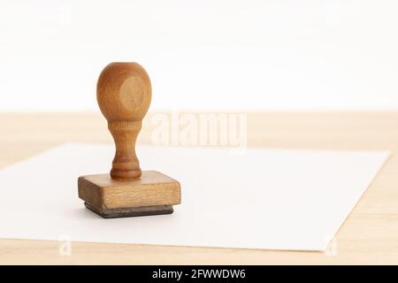 Timbre en caoutchouc vintage et papier vierge sur table en bois. Arrière-plan blanc. Copier l'espace Banque D'Images