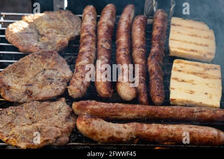 saucisses allemandes, steaks de porc et fromage grillé sur un grill Banque D'Images