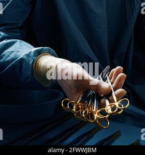 La main gantée d'une infirmière peut contenir plusieurs instruments chirurgicaux, y compris une variété de pinces. Banque D'Images