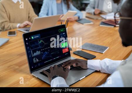 Un jeune financier africain assis devant un ordinateur portable au travail avec des données financières Banque D'Images