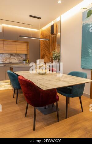 Cuisine moderne et élégante, studio. Grande table avec chaises en velours. Zone dans la salle de séjour, salle à manger, panneau en bois de conception sur le mur. Concept Banque D'Images