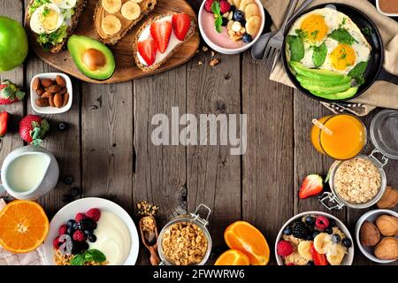 Cadre alimentaire sain pour le petit déjeuner. Scène de table avec fruits, yaourt, smoothie, flocons d'avoine, toasts nutritifs et poêle à œufs. Vue de dessus sur un arrière-plan rustique en bois Banque D'Images