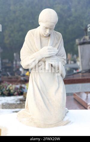 Valenciennes, France, 2017/01/02. Statue d'une jeune fille avec une bougie sur une pierre tombale au cimetière Saint Roch. Banque D'Images